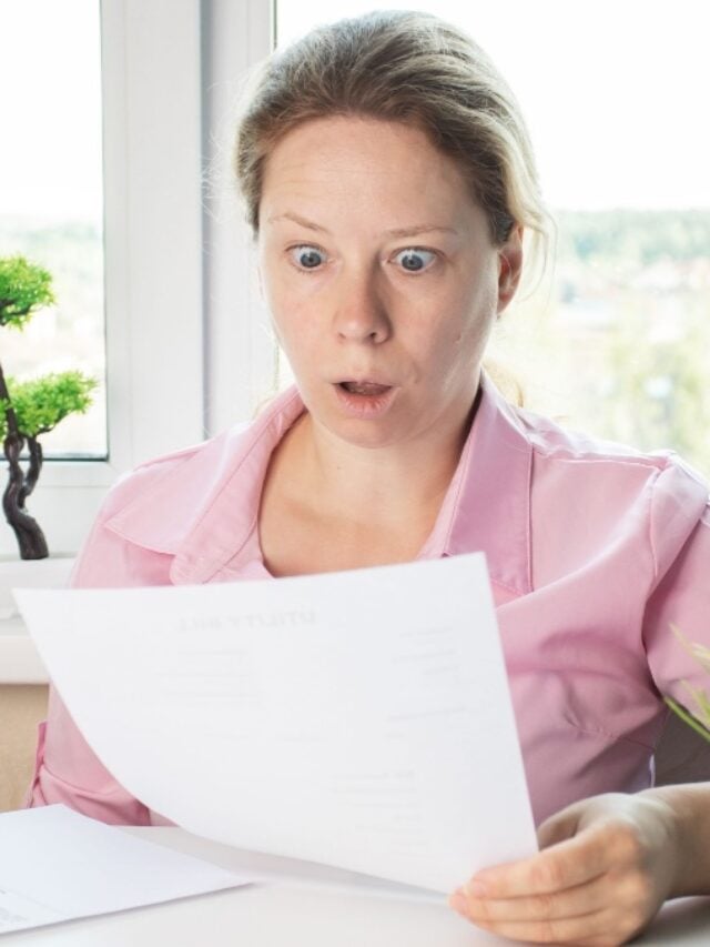 woman surprised by utility bills, Shocked woman looking at letter, reviewing papers with bank documents.