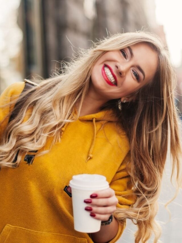 Stylish happy young woman wearing boyfriend jeans, white sneakers bright yellow sweatshirt.