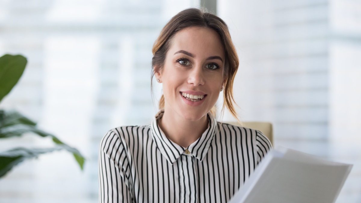Portrait of smiling millennial businesswoman holding documents looking at camera, headshot of happy woman worker or female ceo posing with paperwork.
