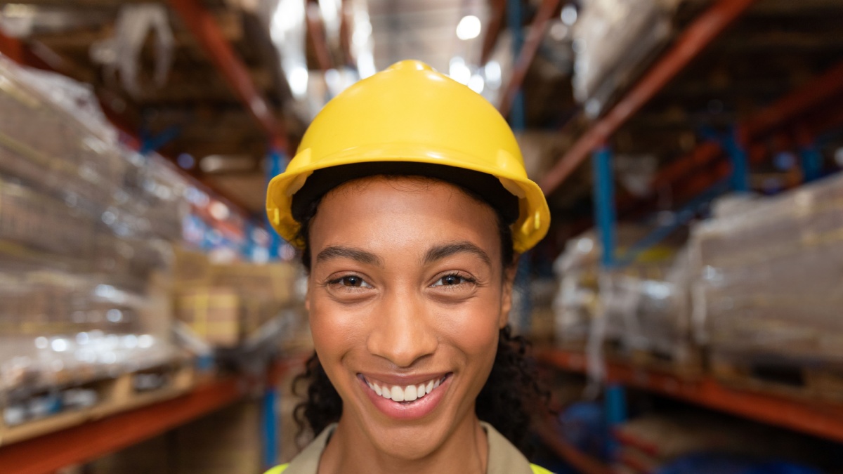 Portrait of happy female worker looking at camera in warehouse.