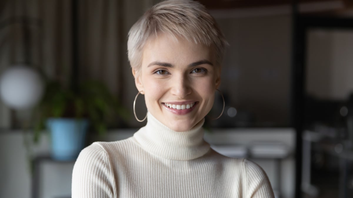 Head shot profile portrait of young happy short haired blonde businesswoman in modern office. Smiling 30s female manager, talented corporate employee,