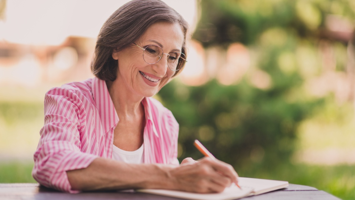 Portrait of positive satisfied person hold pen write take notes diary copybook free time outdoors.
