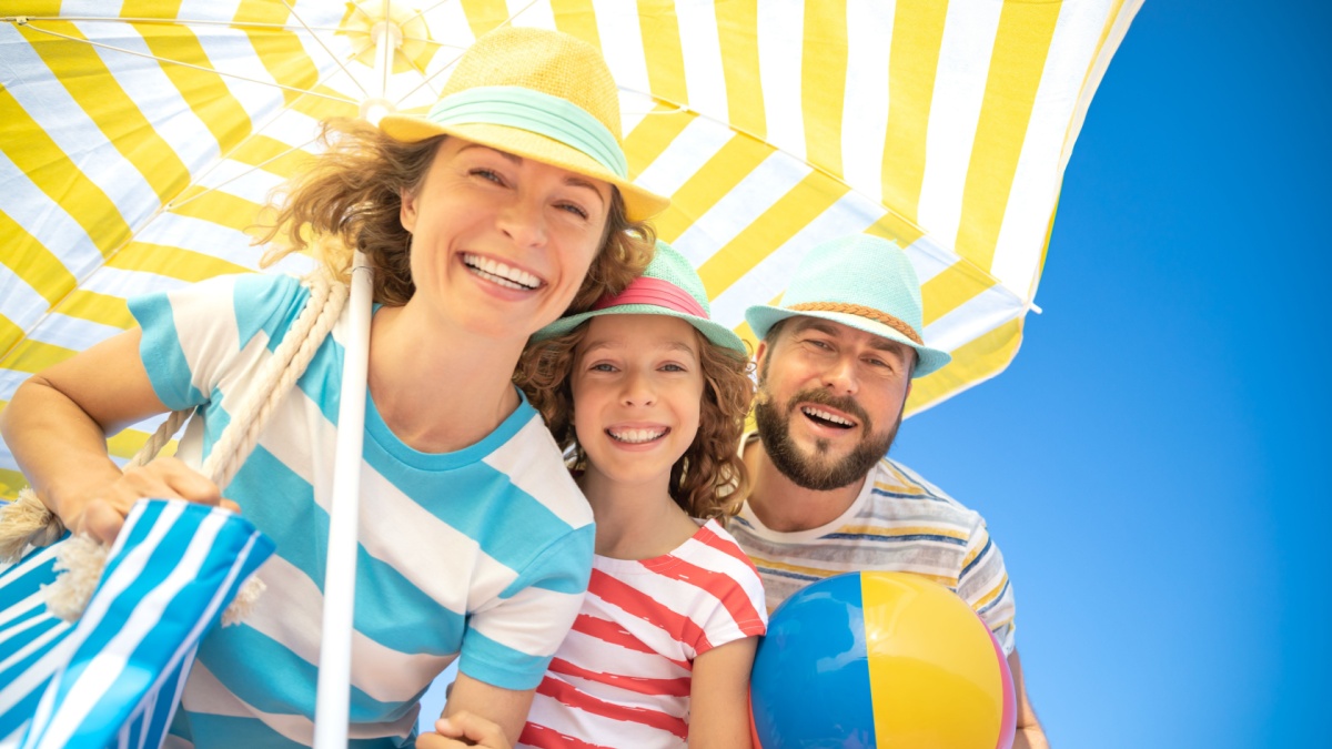 Happy family on summer vacation. Low angle view portrait of happy people against blue sky background.