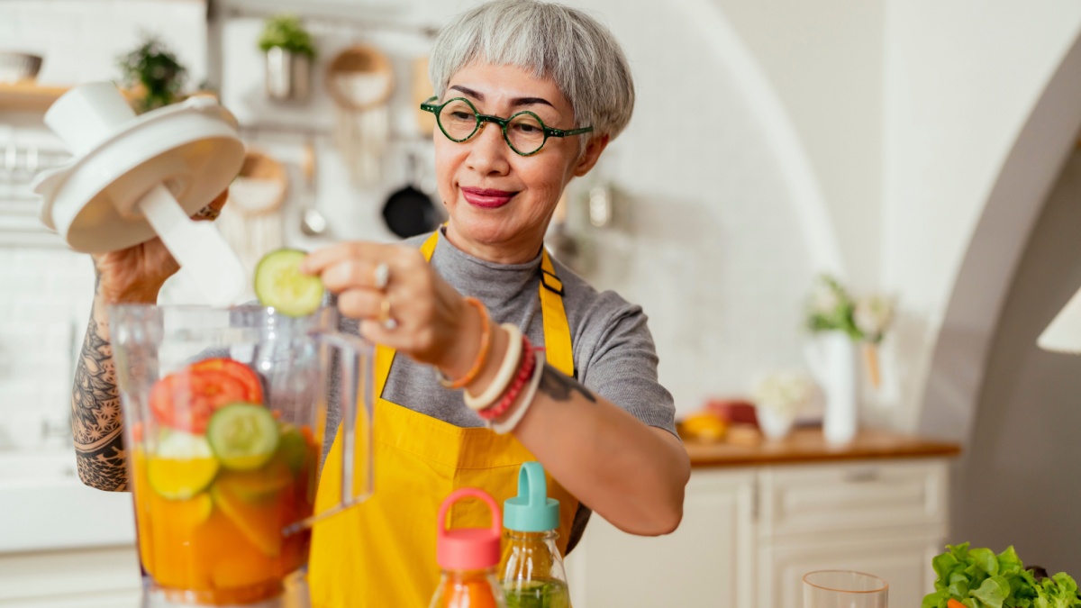 Mature smiling tattoo woman eating salad, fruits and vegetables.