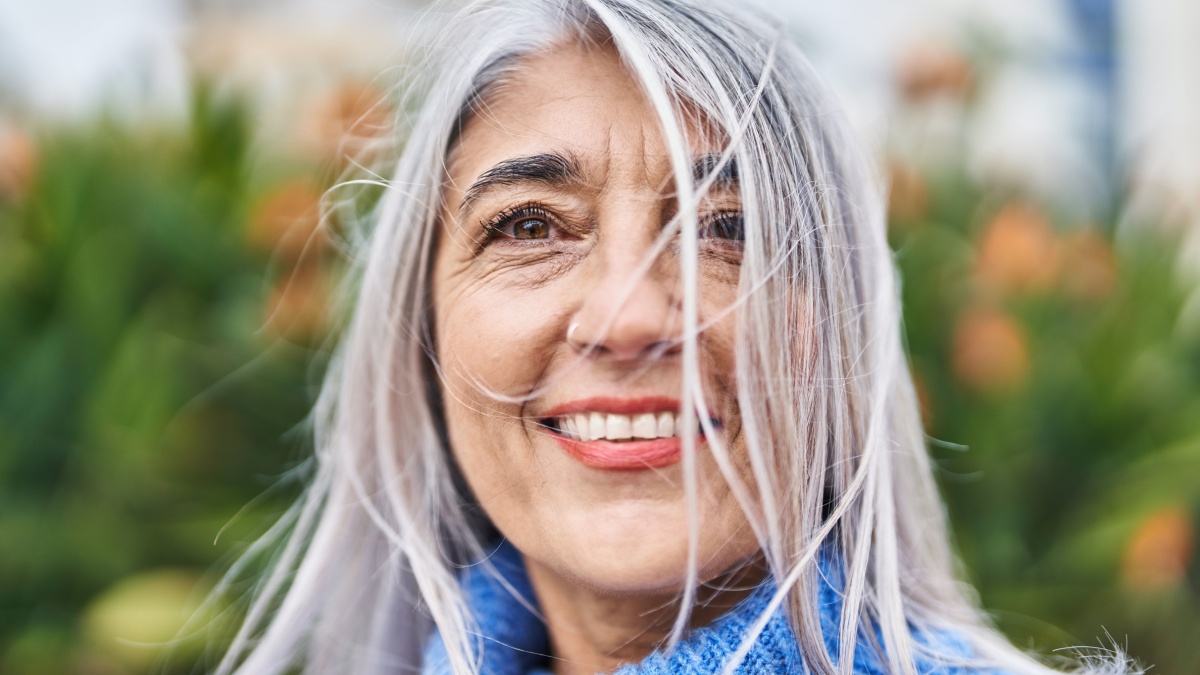 Middle age grey-haired woman smiling confident standing at park.