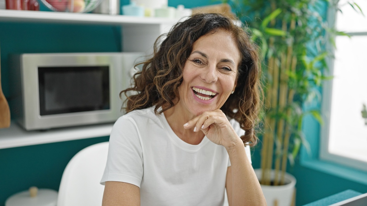 Middle age hispanic woman smiling confident sitting on table at dinning room.