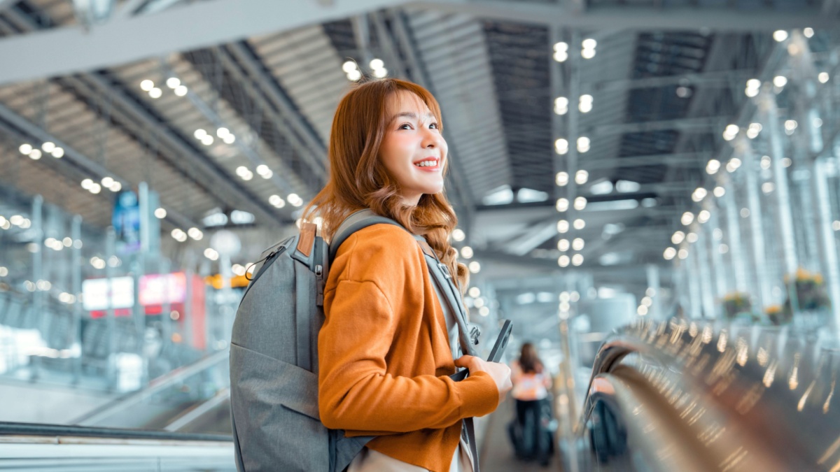 Happy attractive asian woman traveler with backpack at the modern airport terminal, copy space, Tourist journey trip concept.