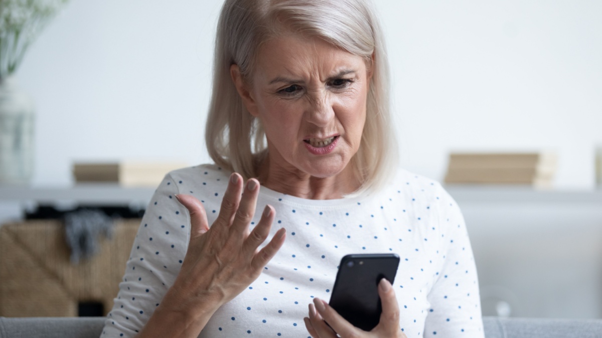 Unhappy middle aged lady irritated by bad smartphone work, head shot close up.