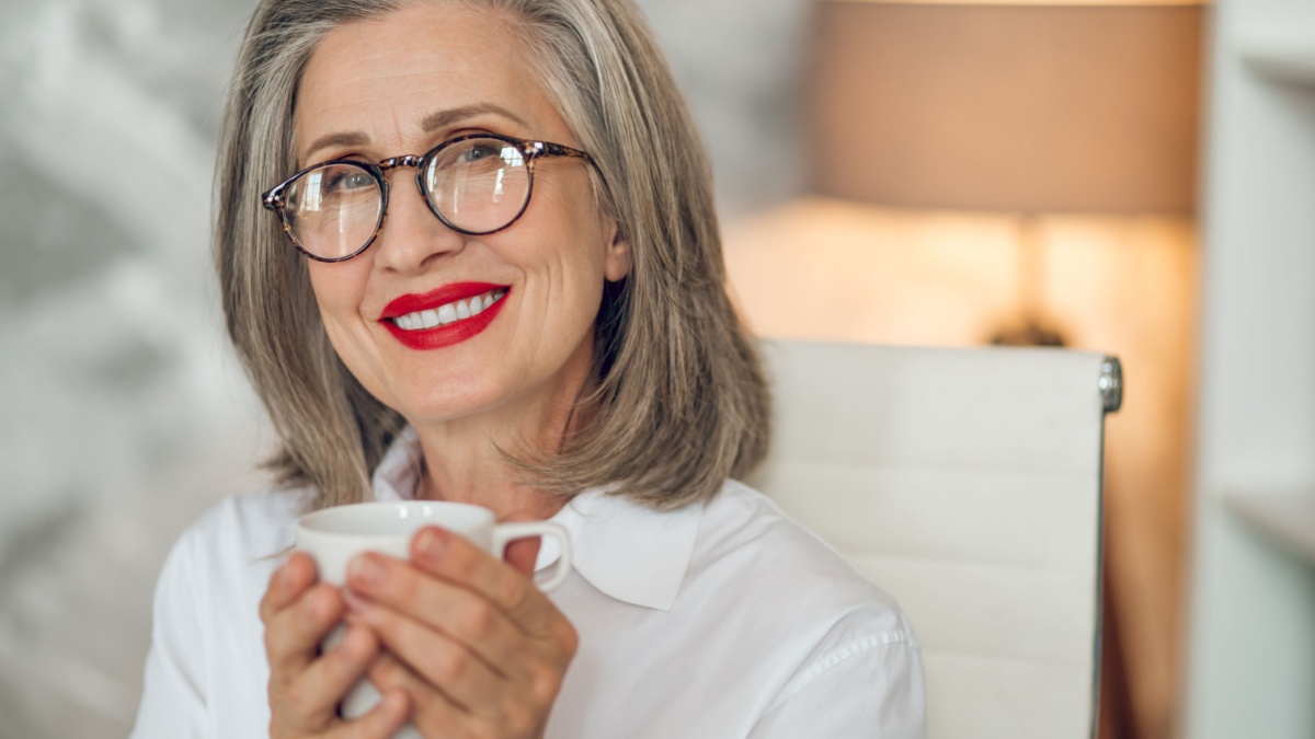 Elegant mature woman having coffee and looking peaceful.