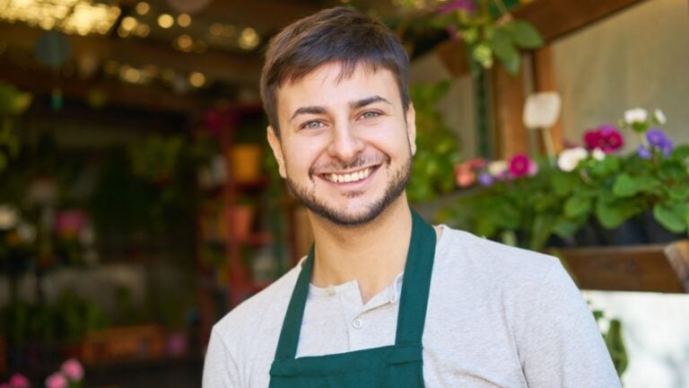 Young man as florist and happy startup founder in flower shop or nursery.
