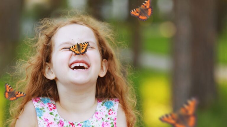 Funny laughing curly girl with a butterfly on his nose. Healthy smile with white teeth.