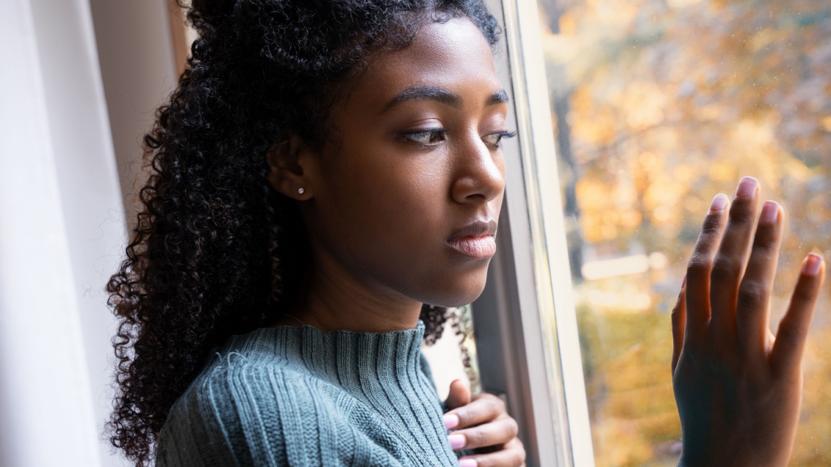 African American female stares outside her window looking out.