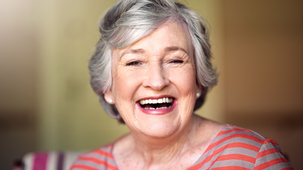 Portrait, nursing home and happy senior woman in living room, laughing in house or relax in retirement.