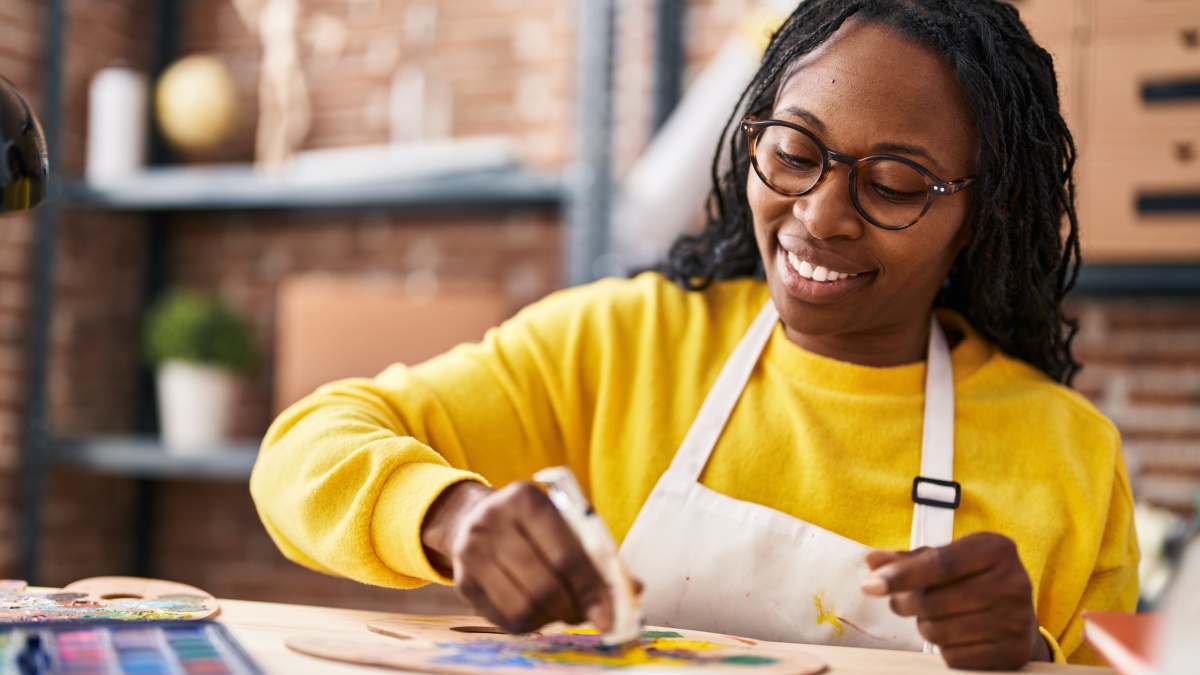 African american woman artist smiling confident mixing color at art studio.