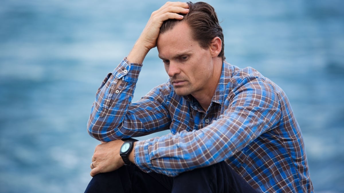An emotional depressed man puts hand on head in frustration battling depression and sadness.