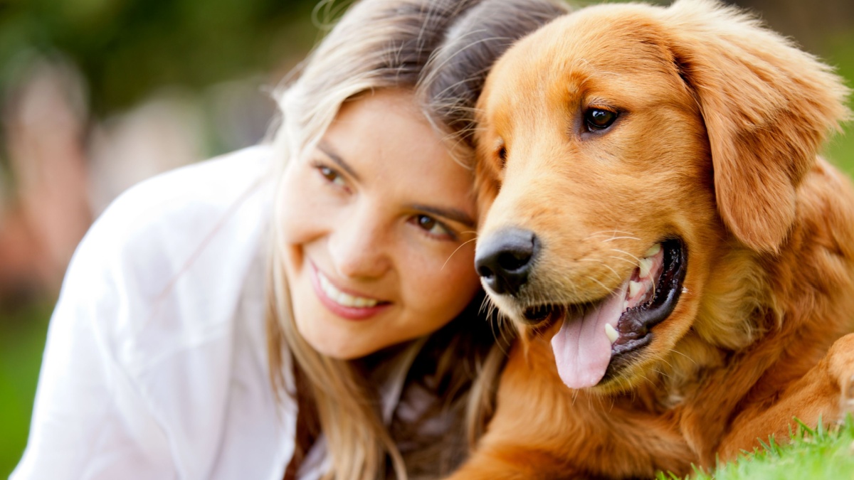 Portrait of a woman with her beautiful dog lying outdoors.