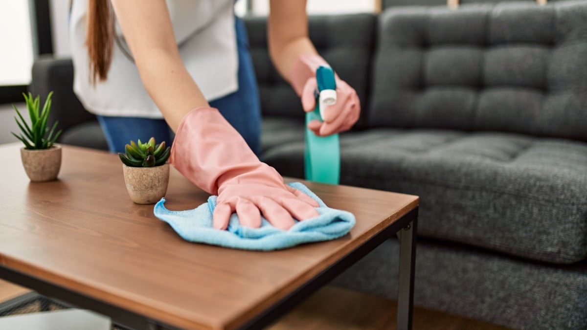 Woman cleaning table using rag and diffuser at home.