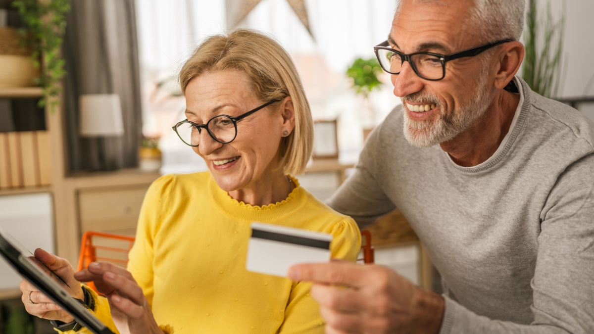 Mature or senior caucasian couple husband and wife shopping online on tablet sit at home happy, positive, relax.