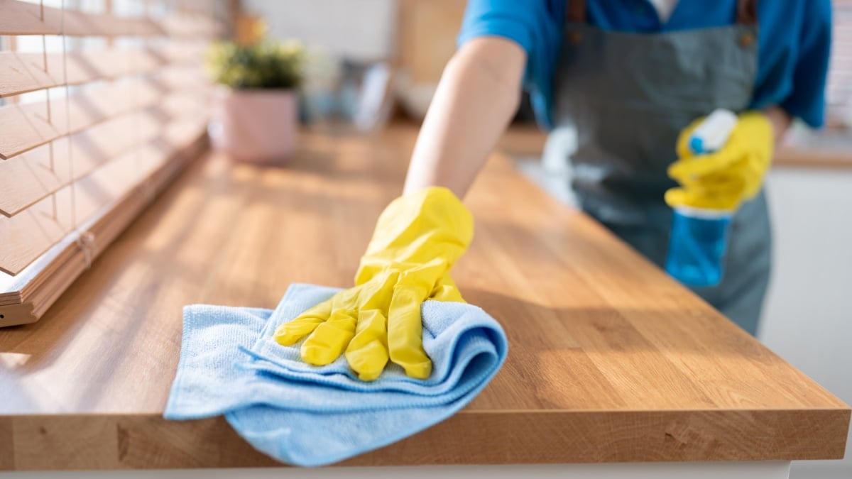 Close up hand cleaning home and wiping with microfiber cloth in kitchen room at home.