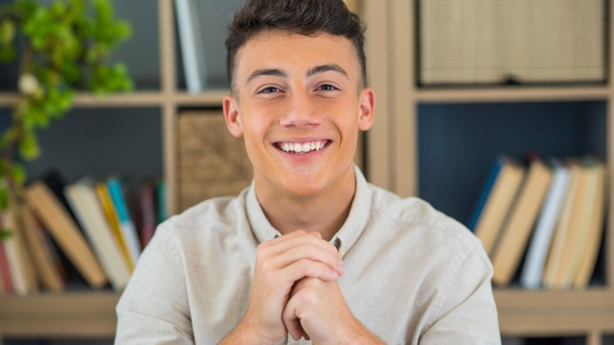 Portrait of one young and happy cheerful man smiling looking at the camera having fun. Headshot of male person working at home in the office.