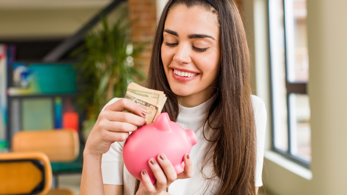 pretty young woman with a piggy bank. savings concept. house interior design.