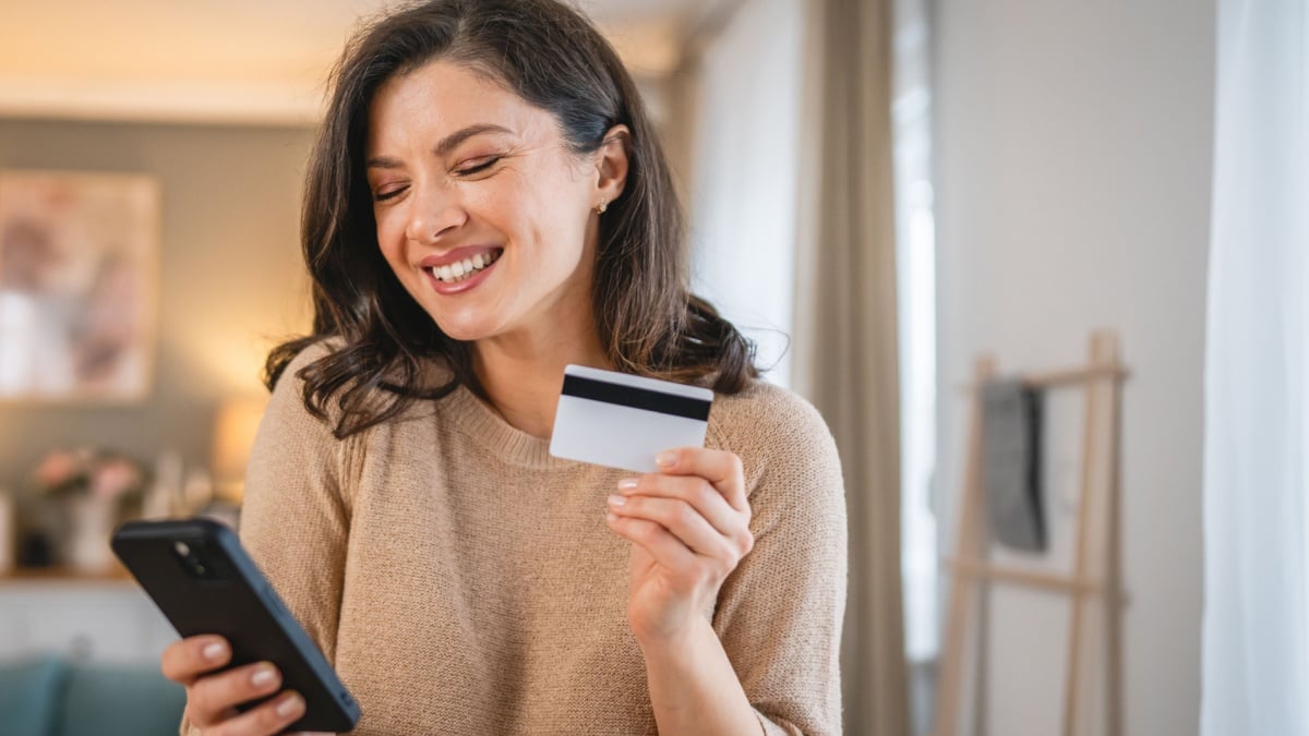 One woman adult caucasian female at home happy smile hold bank credit card and digital tablet online shopping.