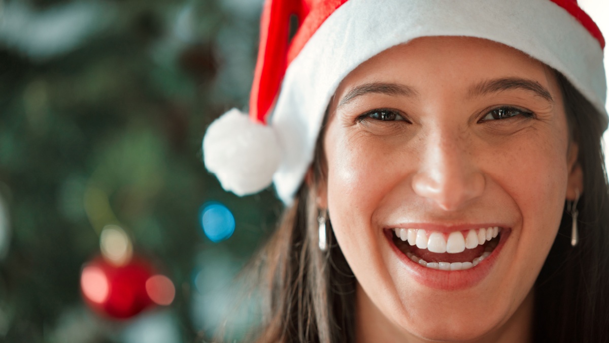 Christmas hat, woman and face with smile in closeup for celebration of winter or December holidays at home.