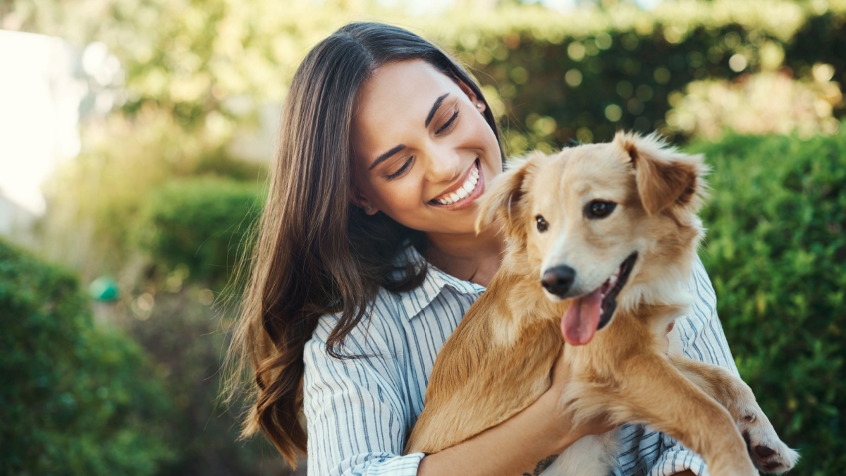 Outdoor, woman and smile for dog hug with bonding time, loyalty and best friends together in garden.