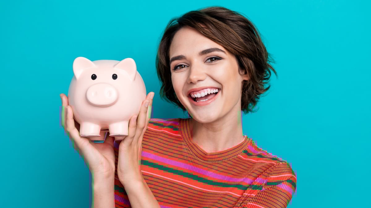 Photo of cheerful cute adorable girl wearing trendy clothes collecting money for financial future isolated on cyan color background.