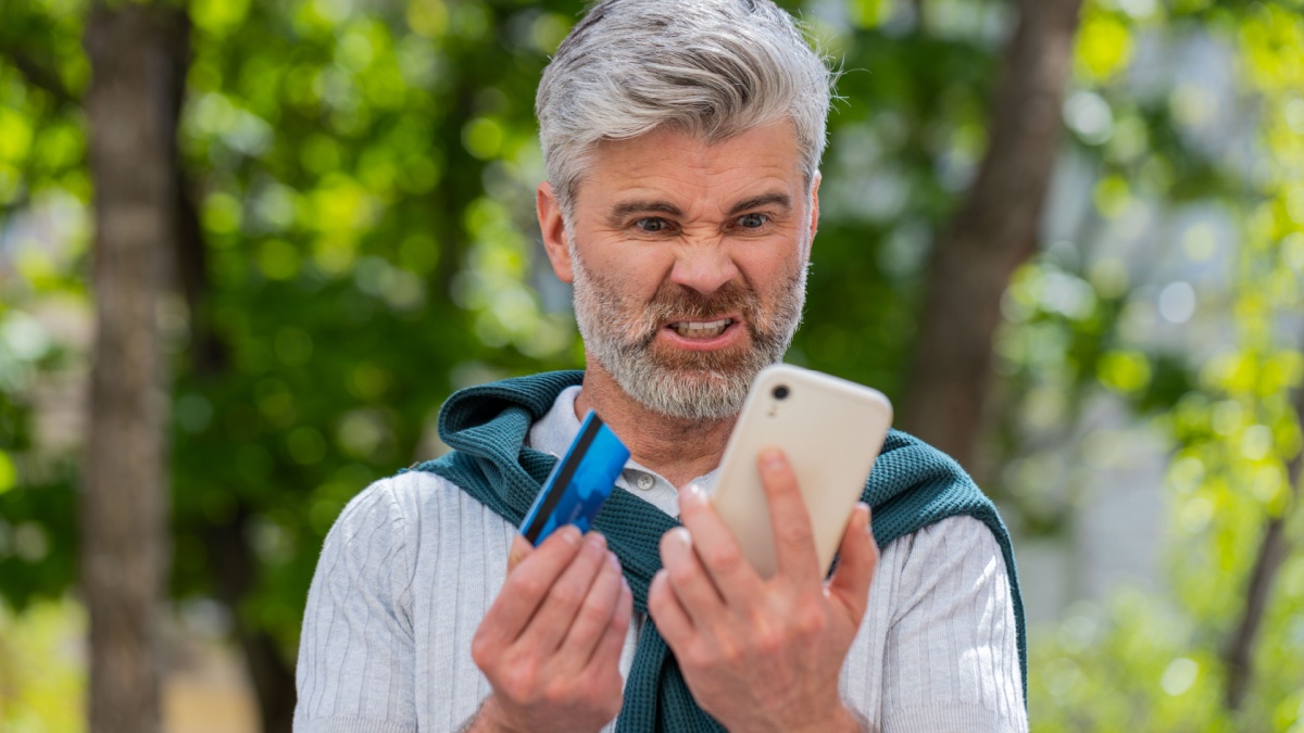 Shocked Caucasian man trying to pay online shopping with smartphone blocked credit card.