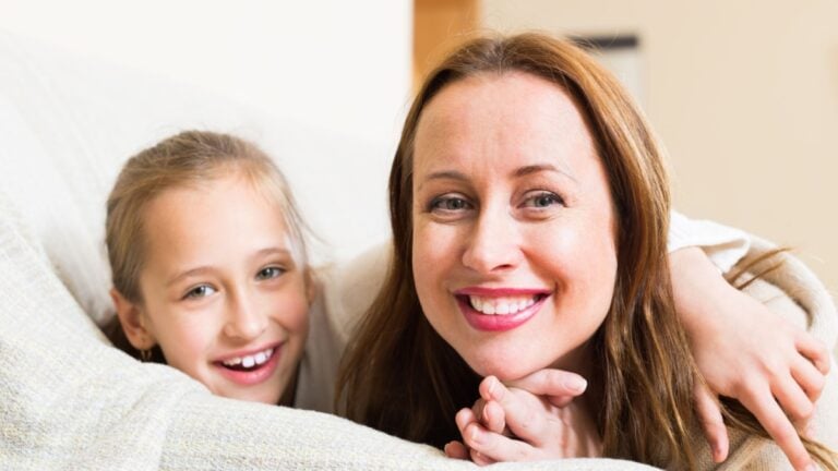 Casual family portrait of cheerful happy mother with smiling little daughter. Focus on woman.