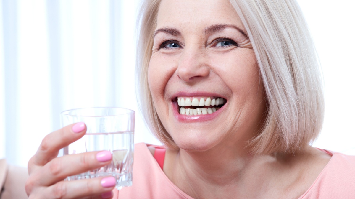 Portrait beautiful middle aged woman drinking water in the morning. Woman's face close up.