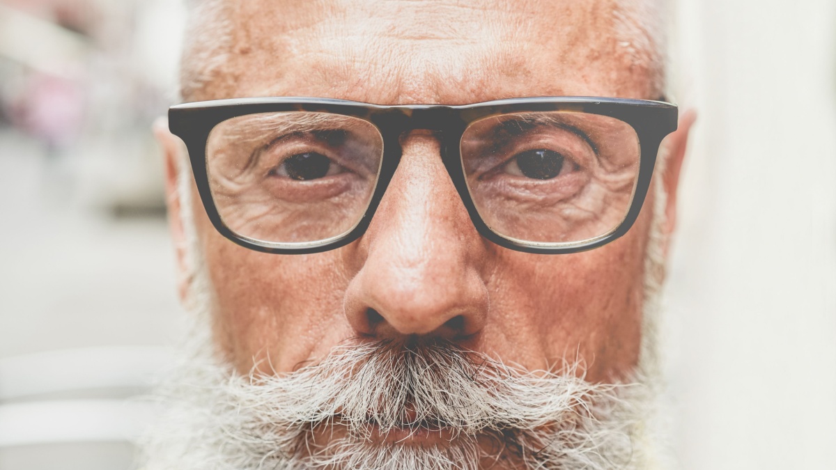 Portrait of middle age trendy man with serious expression - Close up of bearded senior guy - Fashion and elderly lifestyle concept - Focus on glasses.