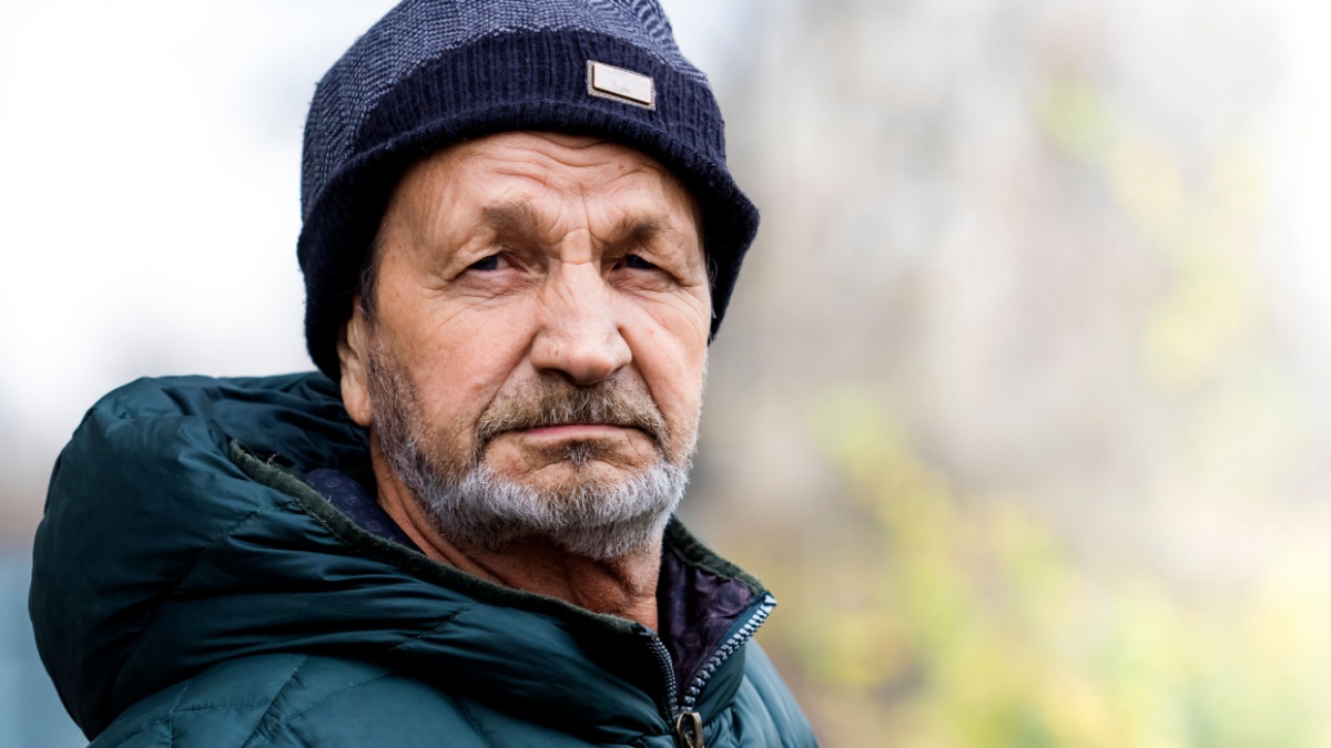 Pensive sad elderly man with a beard and mustache close-up portrait. Russian village.
