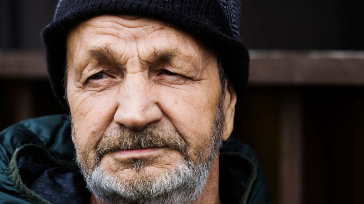 Pensive sad elderly man with a beard and mustache close-up portrait. Russian village.