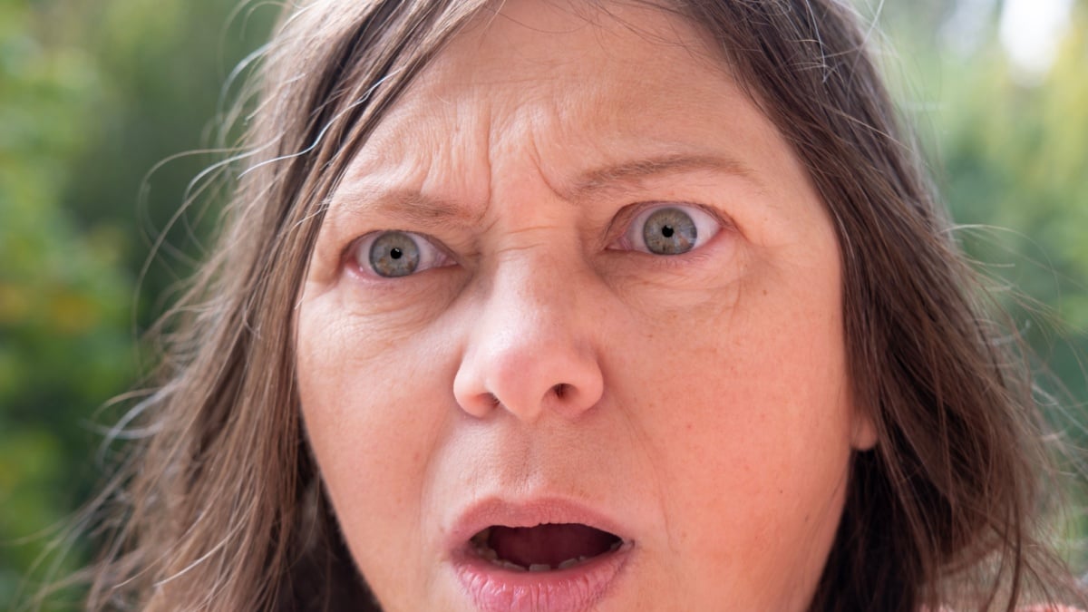 Mature woman, teacher, woman 50s in pink jacket with planner very surprised, screams indignantly.