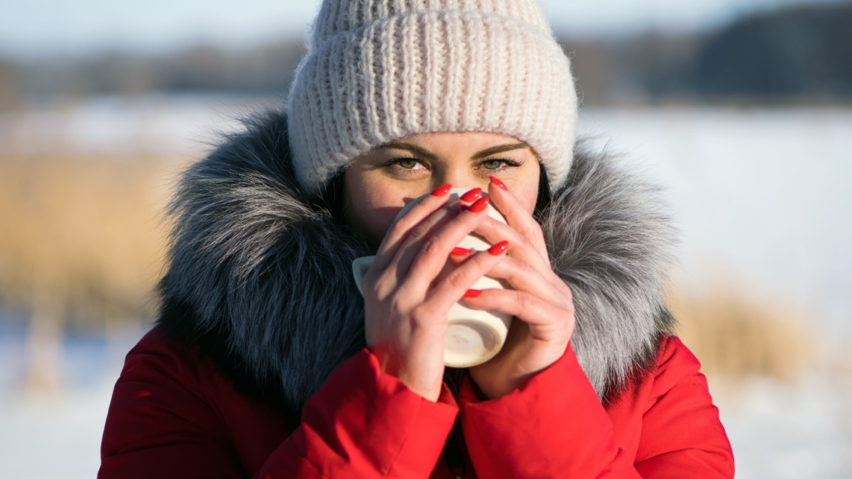 photo woman in the winter forest. hot drinks, warm up with tea.