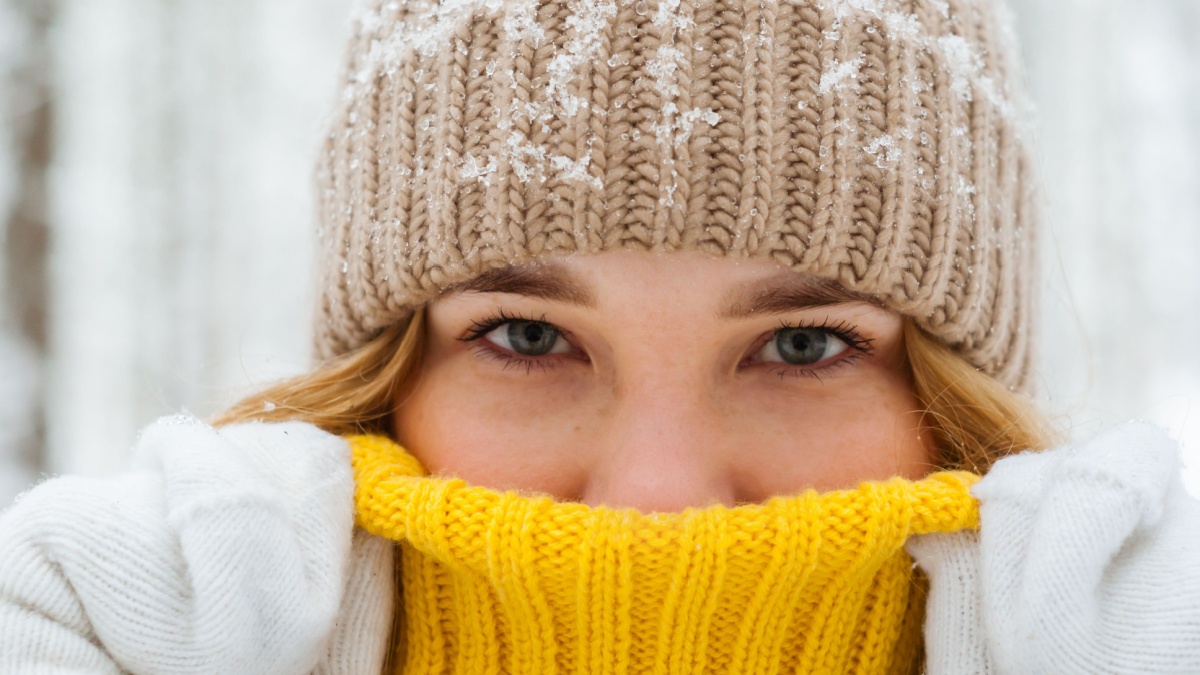 portrait of a girl warming up with her breath, hiding her nose in the collar of a warm sweater, close-up.