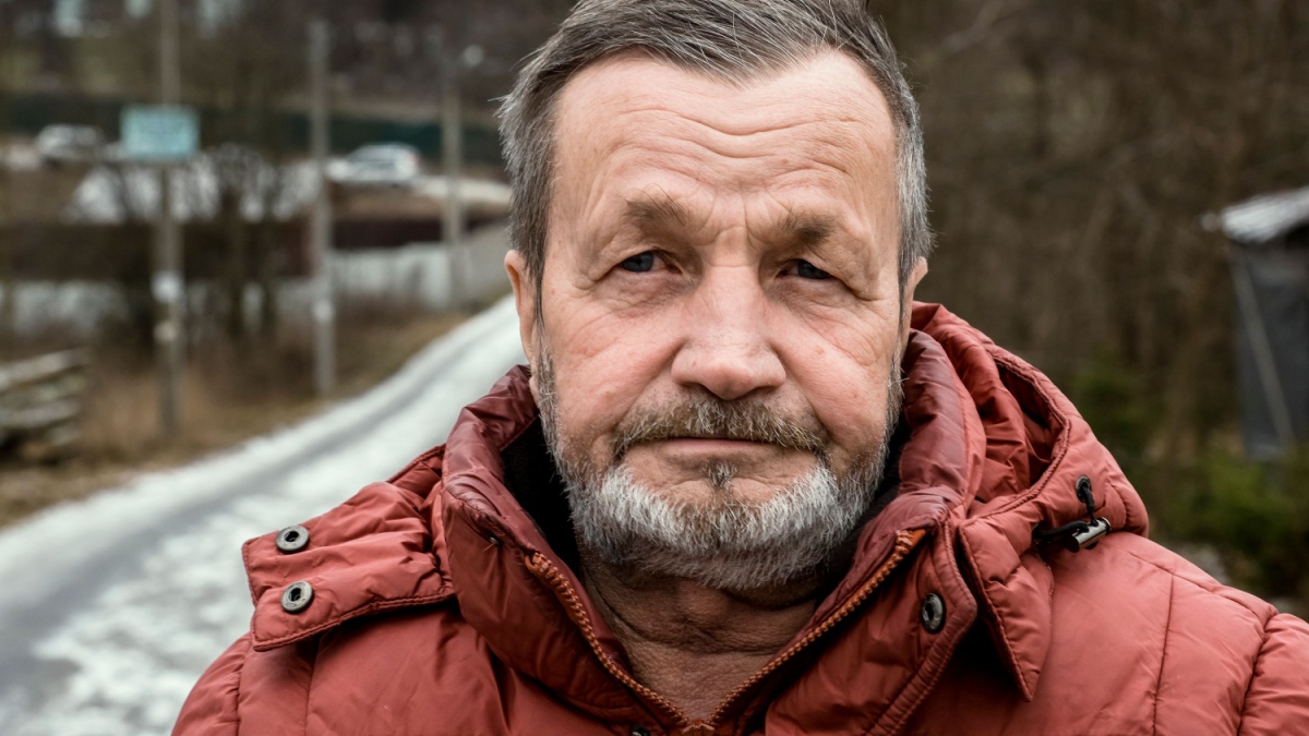 Pensive elderly bearded man face, winter portrait outdoors in a Russian village.