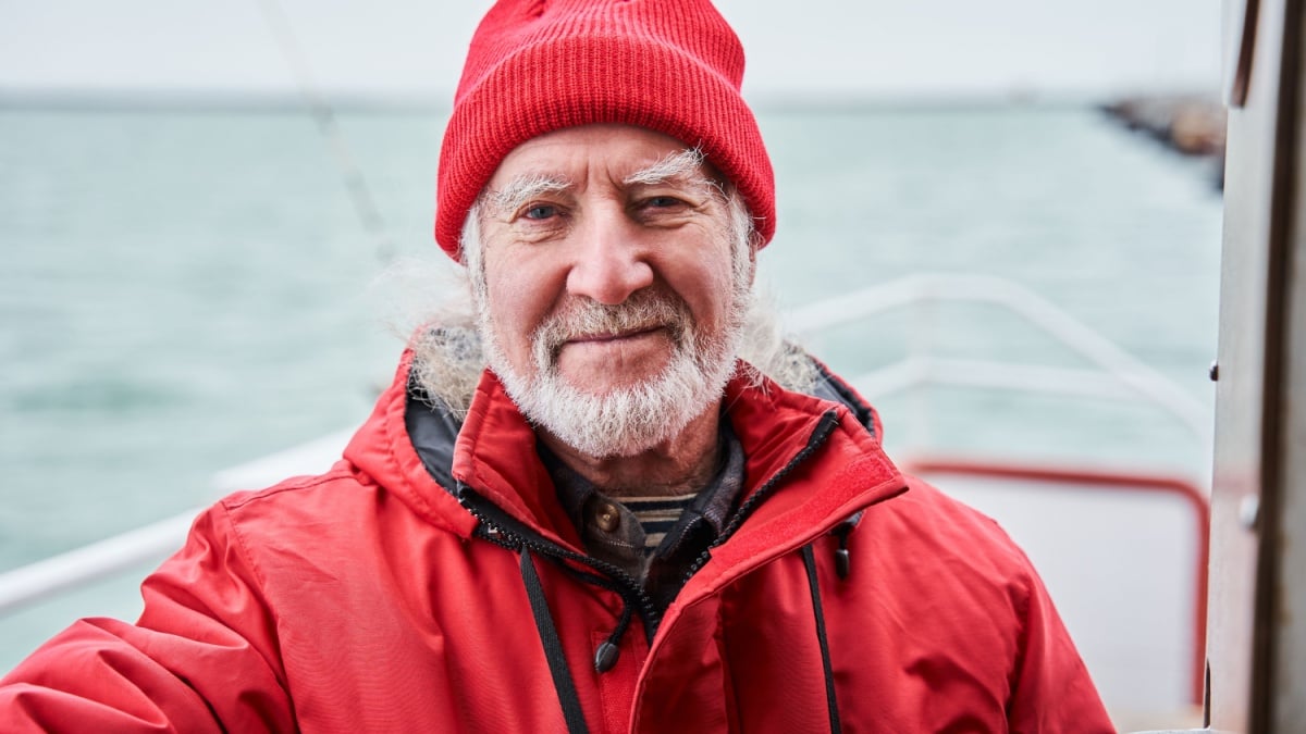 Portrait view of the marine chief officer or captain on deck of vessel or ship looking at the camera. Sailing, age, tourism, travel and people concept.