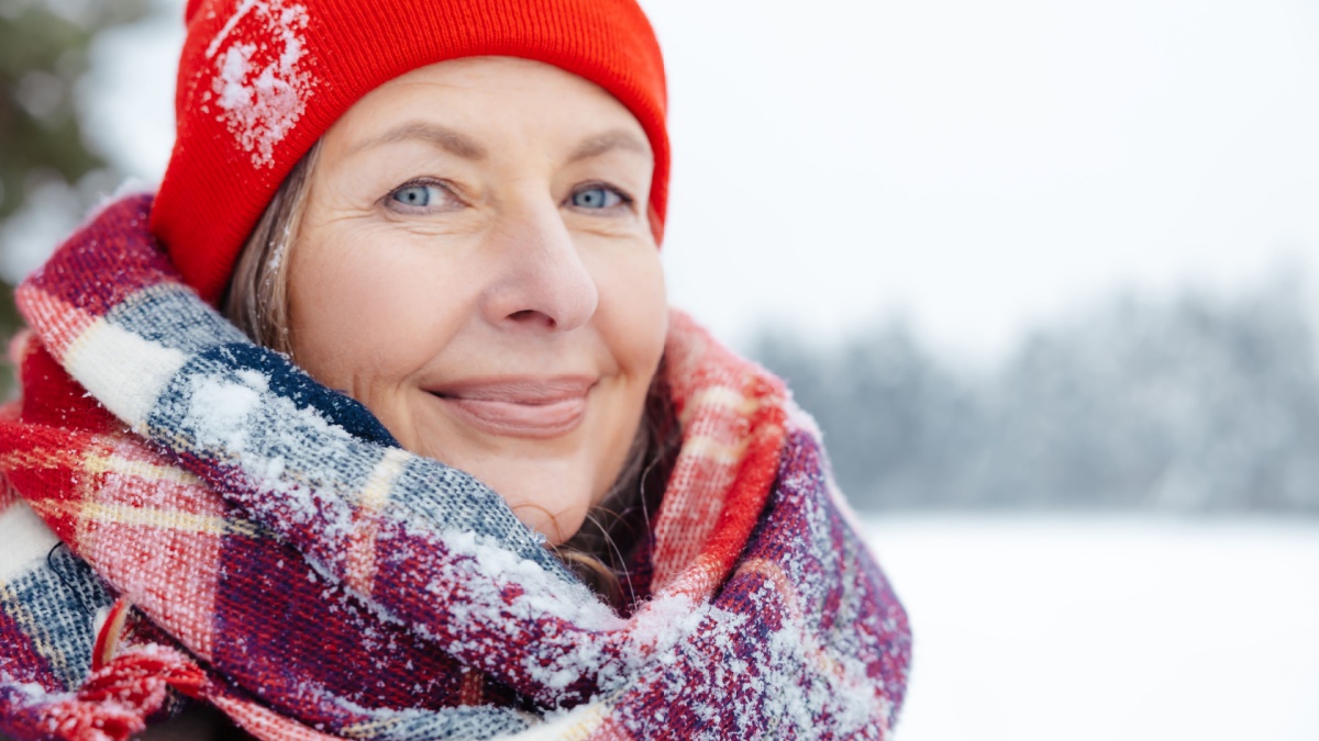 Headshot of a smiling mature woman in red and checkered scarf.