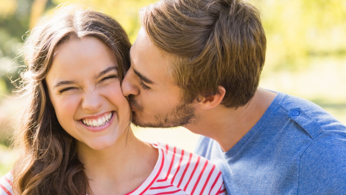 Cute couple kissing in the park on a sunny day.
