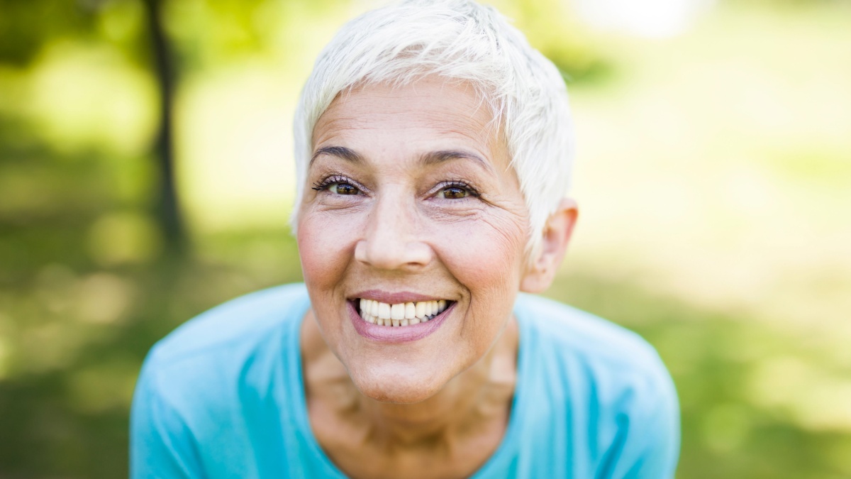 Portrait of a smiling sporty senior woman in a park at summer day.
