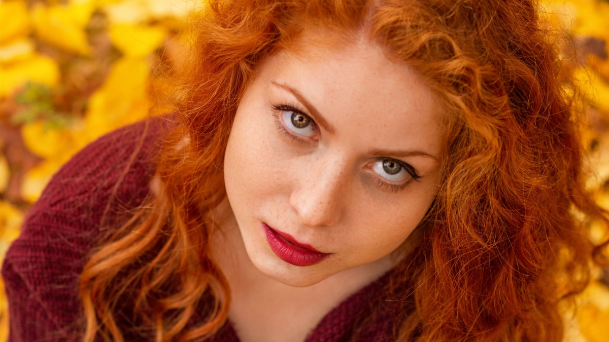 portrait of a beautiful red-haired girl in yellow leaves.