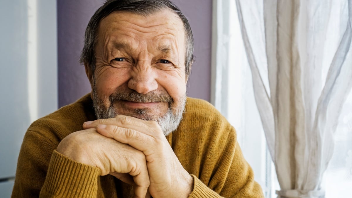 Smiling elderly man at home by the window.