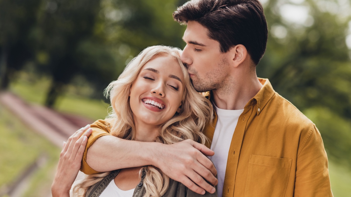 Portrait of beautiful handsome adorable couple kissing cuddling enjoying idyllic pastime honey moon outdoors.