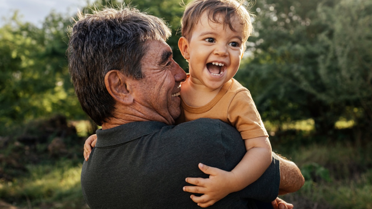 Playful grandfather spending time with his grandson in park on sunny day.