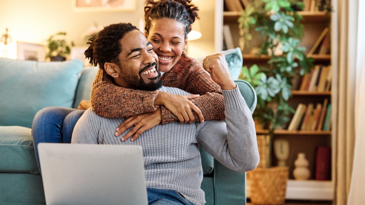 Young happy black couple having fun using a laptop at home.