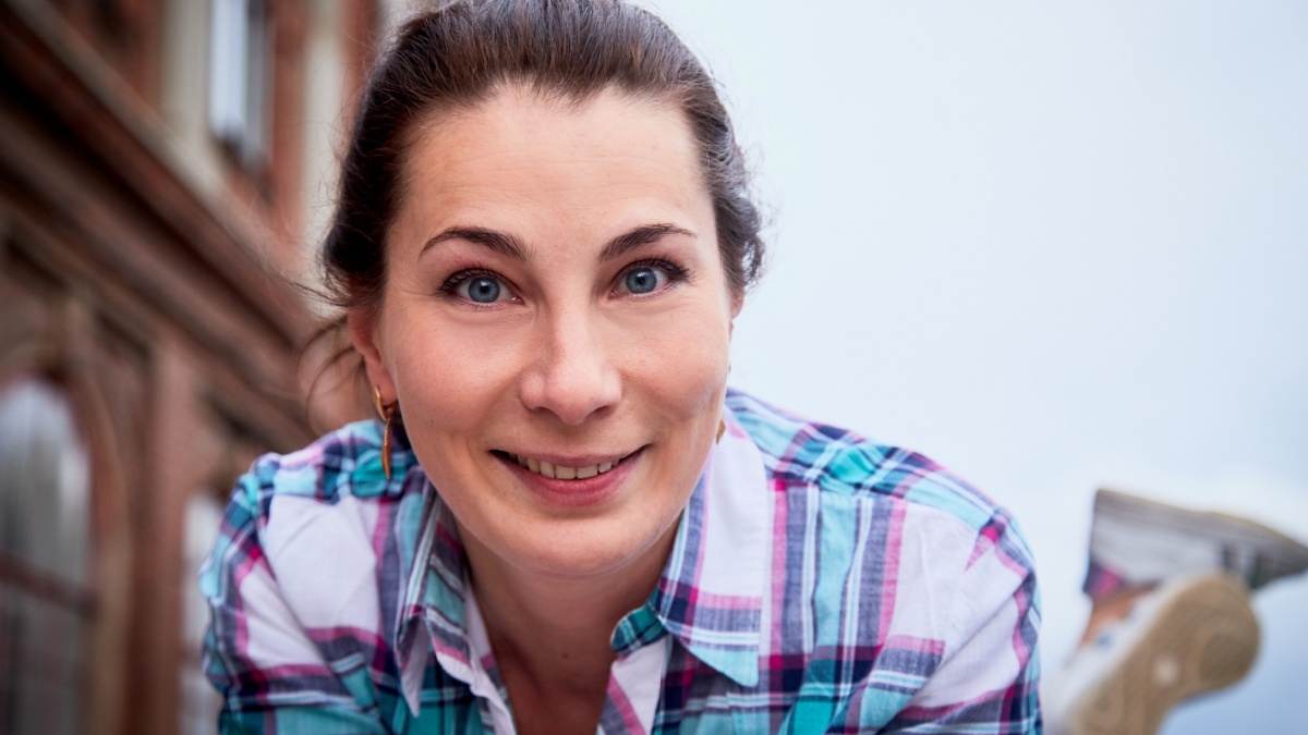 Brunette girl near near the facade of a large red brick building with windows in the Central part of the ancient city. Walk in downtown. Portrait of a funny pretty girl on the street of the town.
