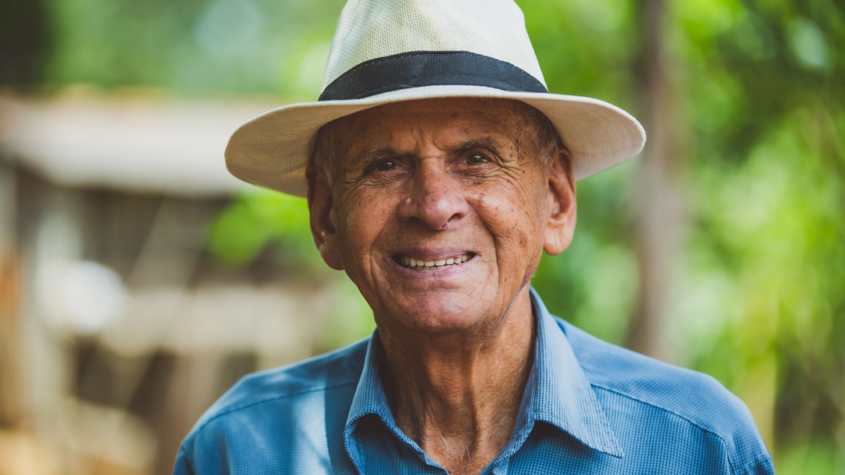Portrait of smiling beautiful older male farmer. Elderly man at farm in summer day. Gardening activity. Brazilian elderly man.